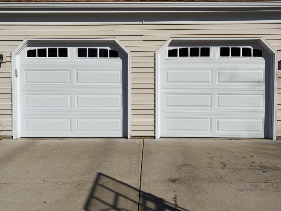 Two new white raised-panel garage doors with windows