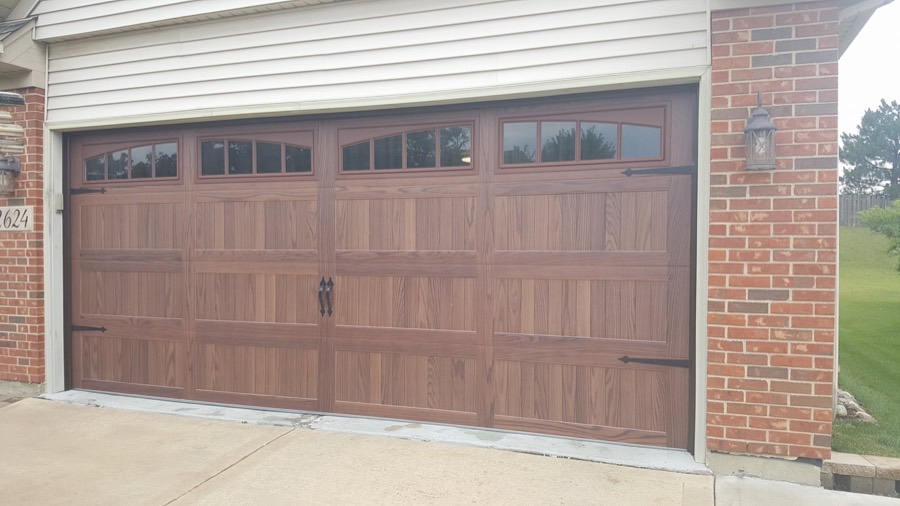 Wood-grain finish garage door with carriage hardware